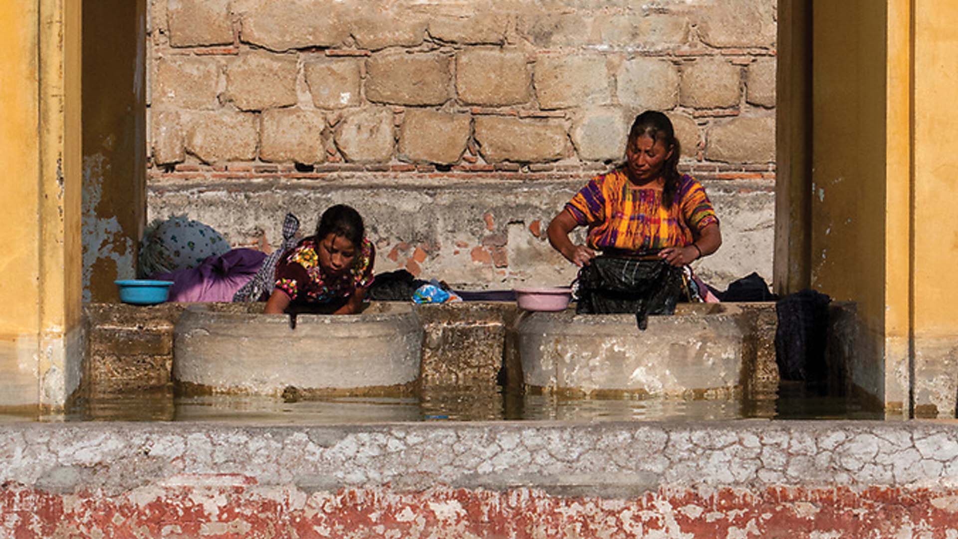 two women doing laundry at Public Pila in Antigua, Guatemala